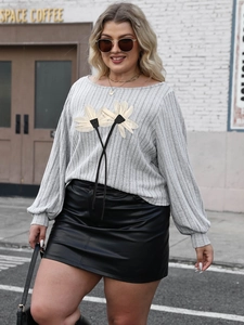 Detail of grey ribbed knit top featuring 3D daisy applique and black ribbon accents