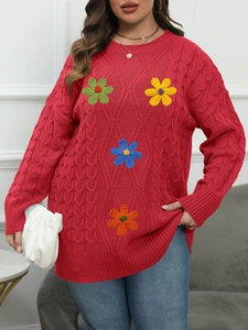 Close-up of red cable knit sweater with colorful embroidered flowers and textured stitching