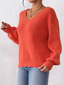 Dettaglio del maglione lavorato a maglia arancione brillante con scollo a V e trama a coste