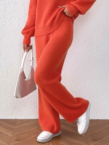 Detail of orange knitted two-piece set featuring wide-leg pants and ribbed texture fabric