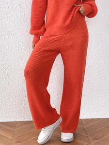 Macro shot of orange knit fabric texture on high-waist wide-leg straight trousers