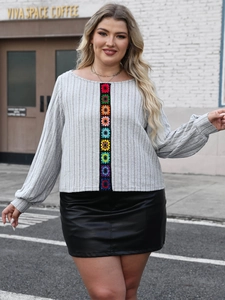 Detail of colorful crochet flower trim on a grey ribbed long sleeve top with a leather skirt