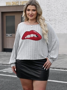 Close-up of a grey striped knit top with a red sequin lip print and black leather skirt