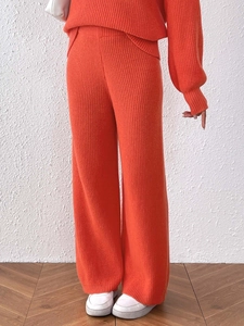 Close-up of orange ribbed knit fabric texture on high-waisted wide-leg trousers