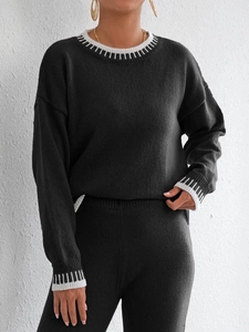 Dettaglio dei motivi in maglia a righe a contrasto su scollo e polsini del maglione nero