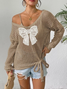 Detail von khakifarbenem Lochstrickpullover mit weißer Spitzenschleife und Bändern