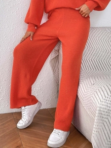 Detailed texture of thick orange knitted fabric on high-waist wide-leg casual pants