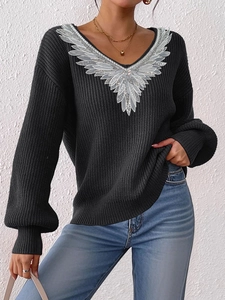 Detail of sequined wing embroidery on V-neck black knit sweater with lantern sleeves