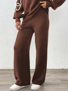Dettaglio dei pantaloni in maglia marrone scuro a vita alta con drappeggio e trama eleganti