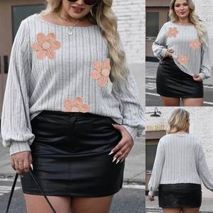 Detail of grey ribbed long sleeve top featuring large floral embroidery and textured fabric