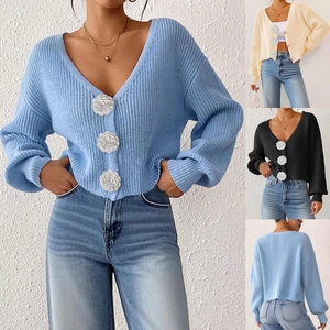 Detail of knit cardigan showing three 3D white flower buttons and ribbed texture