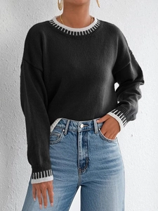 Dettaglio dei polsini a contrasto a righe su un maglione nero in maglia da donna