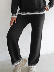 Détail d'un pantalon en maille à ourlet rayé, faisant partie d'un ensemble noir décontracté