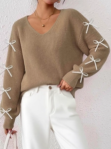 Close-up detail of khaki V-neck ribbed knit sweater with decorative white ribbon bows