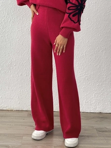 Detail of red knit set featuring black floral embroidery on long sleeves and wide-leg trousers