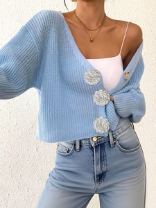 Detail of light blue knit cardigan featuring white 3D flower buttons and soft texture