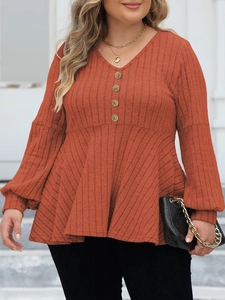 Detail of V-neck ribbed top featuring golden decorative buttons and brick red texture