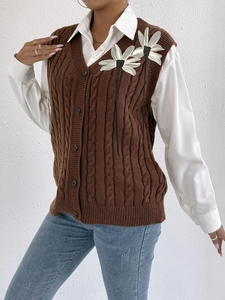 Detail of cable knit brown vest with 3D white floral appliques and ribbon stems