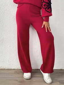Detail of rose red knit lounge set with black floral applique embroidery on sleeves