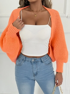 Detailaufnahme der orangefarbenen Grobstrickjacke mit Ballonärmeln und goldener Kette