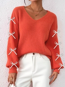 Women's orange V-neck knit sweater with white ribbon bow details on sleeves