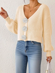 Detail of knit cardigan with large white camellia flower buttons and thick knit texture