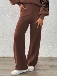 Detail of brown knitted wide-leg pants with elegant floral embroidery on the sleeve