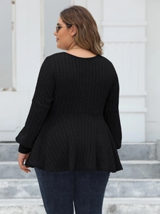 Plus size black ribbed knit top with long sleeves and peplum waist on a model