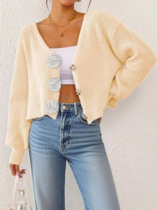 Detail of cream knit cardigan featuring large 3D white rose flower decorative buttons