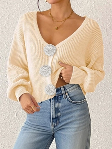 Detailed knit texture and 3D floral accents on a cream-colored V-neck cardigan sweater