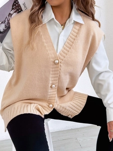 Détail d'un gilet en tricot beige avec des boutons nacrés et des bords-côtes