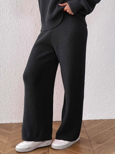 Detail of black ribbed knit wide-leg trousers with thick vertical texture and drape