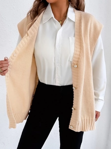 Détail du gilet en maille abricot avec boutons perles et texture côtelée