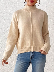 Detail view of cream knit sweater showing vertical seam design and ribbed cuffs