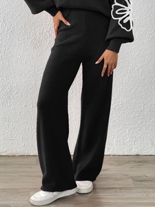 Detailed view of black knit lounge set featuring white floral embroidery on the sleeves