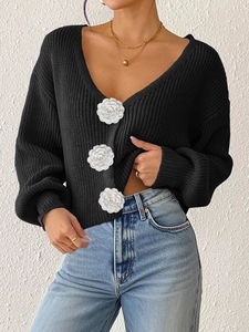 Detail of black V-neck knitted cardigan with three 3D white camellia flower buttons