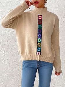 Detail of colorful bohemian crochet flower pattern on beige high-neck knit sweater
