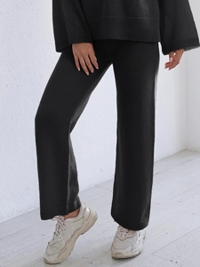 Detail of black knitted two-piece set featuring wide-leg pants and long sleeve top