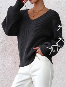 Detail of V-neck charcoal knit sweater featuring white ribbon bows on the long sleeve