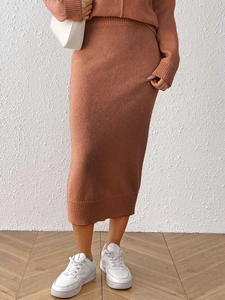 Detail of brick red knitted midi skirt hemline with ribbed texture and soft fabric