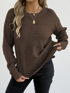 Detailed close-up of dark brown knit sweater texture with round neck and gold necklace