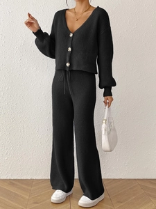 Detail of black knit two-piece set featuring V-neck cardigan buttons and drawstring pants