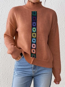 Detail of colorful crochet floral embroidery on a brown high-neck knit sweater for women