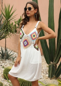 Détail du motif floral coloré crocheté à la main sur la robe de plage blanche