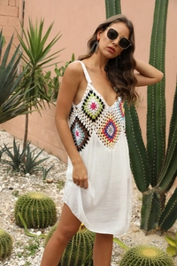 Détail du corsage en crochet coloré et col en V sur robe de plage blanche bohème