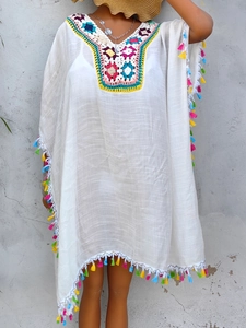 Detail of colorful crochet neckline and fringe tassels on a white beach cover-up dress