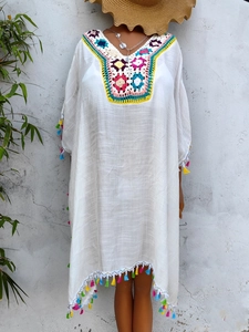Detail of colorful crochet neckline and white mesh fabric on a bohemian beach dress