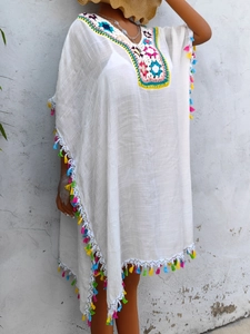 Detail of bohemian beach cover-up with colorful crochet V-neckline and vibrant fringes