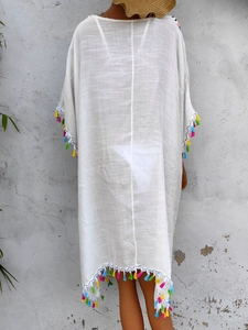 Detail of colorful tassel fringes on a white crochet beach cover-up dress back