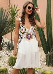 Détail du corsage en crochet coloré sur une robe de plage bohème blanche